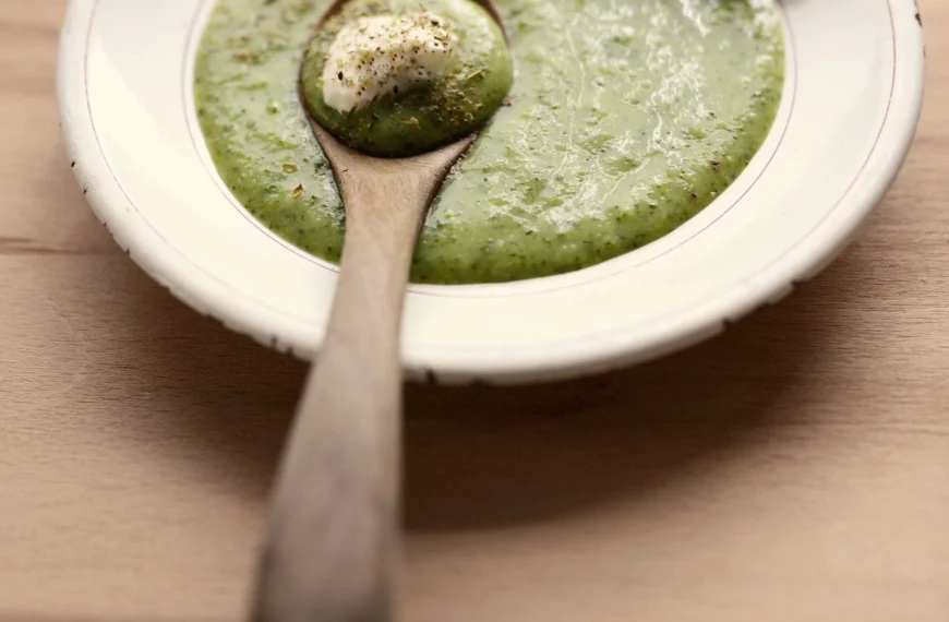 bowl of creamy vegetable soup(Jason's Deli Broccoli Cheese Soup) with a wooden spoon resting on the bowl